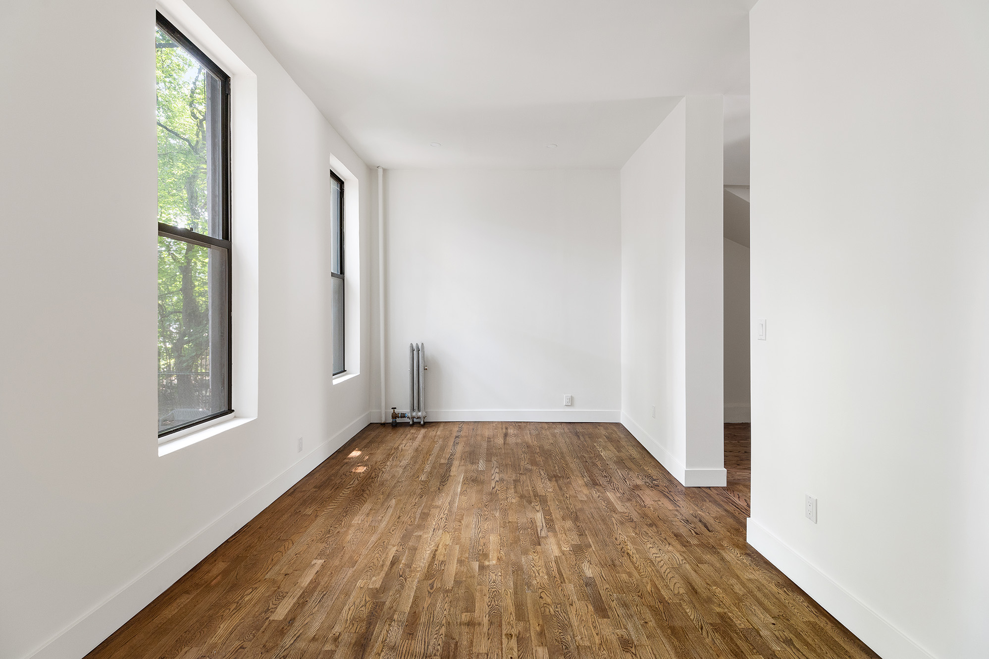306 Gates Avenue, Unit 1A Brooklyn, NY 11216 - Photo 2 of 14 an empty room with wooden floor and windows