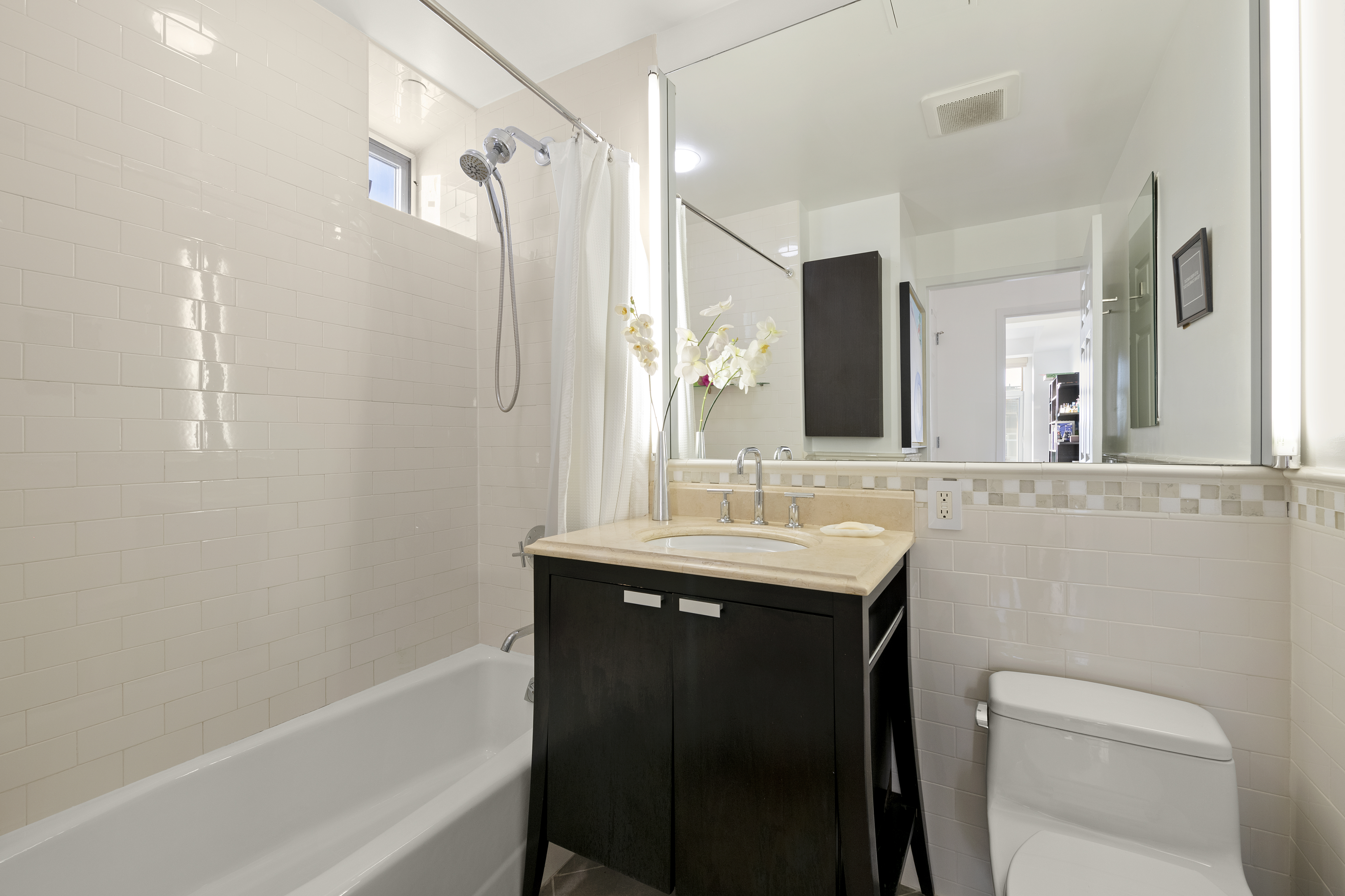 106 West 116th Street, Unit 10B Manhattan, NY 10026 - Photo 7 of 12 a bathroom with a bath tub sink mirror vanity and toilet