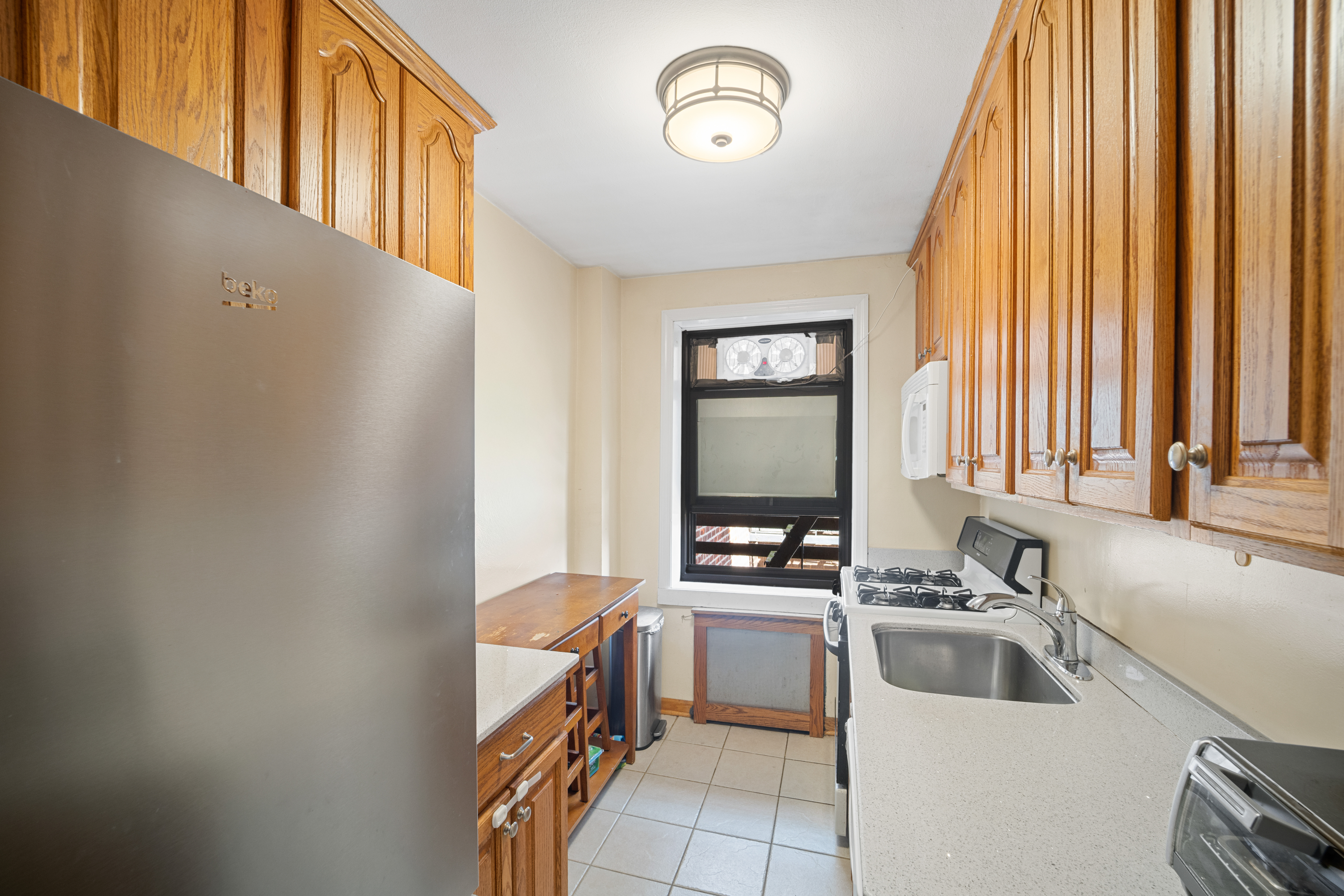 211-01 75th Avenue, Unit 4O Queens, NY 11364 - Photo 13 of 19 a kitchen with a sink cabinets and a window