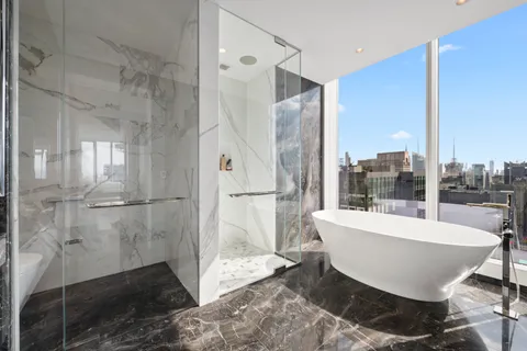 a large white bath tub sitting in a bathroom with a tub and shower