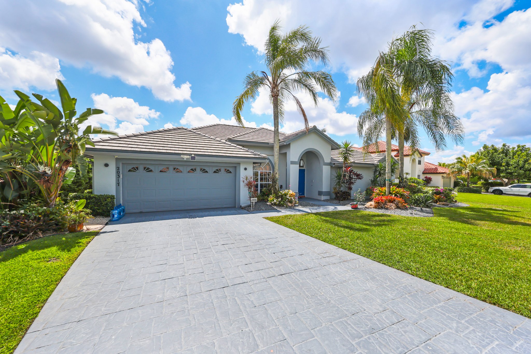 20317 Hacienda Court Boca Raton, FL 33498 - Photo 5 of 100 a view of a white house with a big yard and a large tree