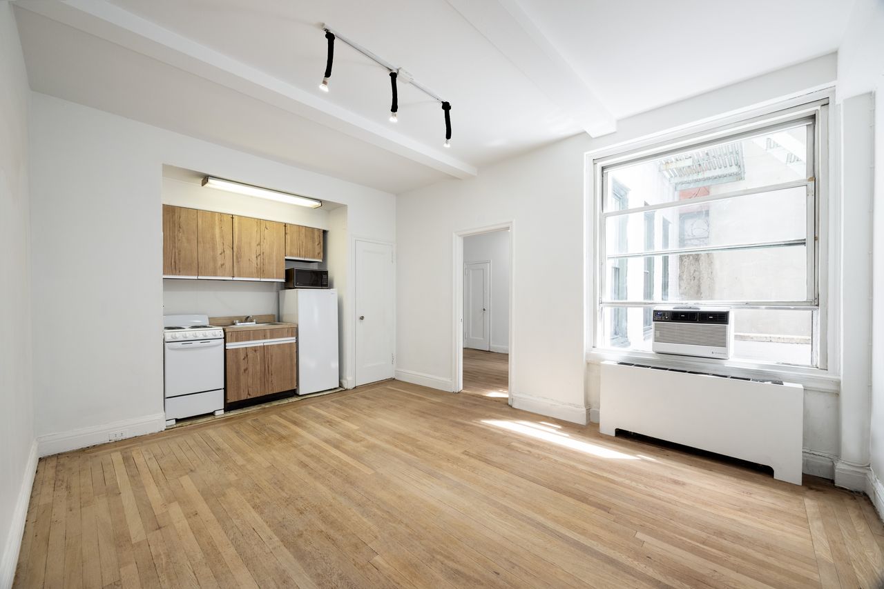 325 West 45th Street, Unit 108 Manhattan, NY 10036 - Photo 2 of 12 a kitchen with stainless steel appliances a white cabinets and a wooden floor