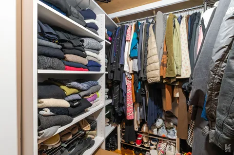 a view of walk in closet with clothes and shoes