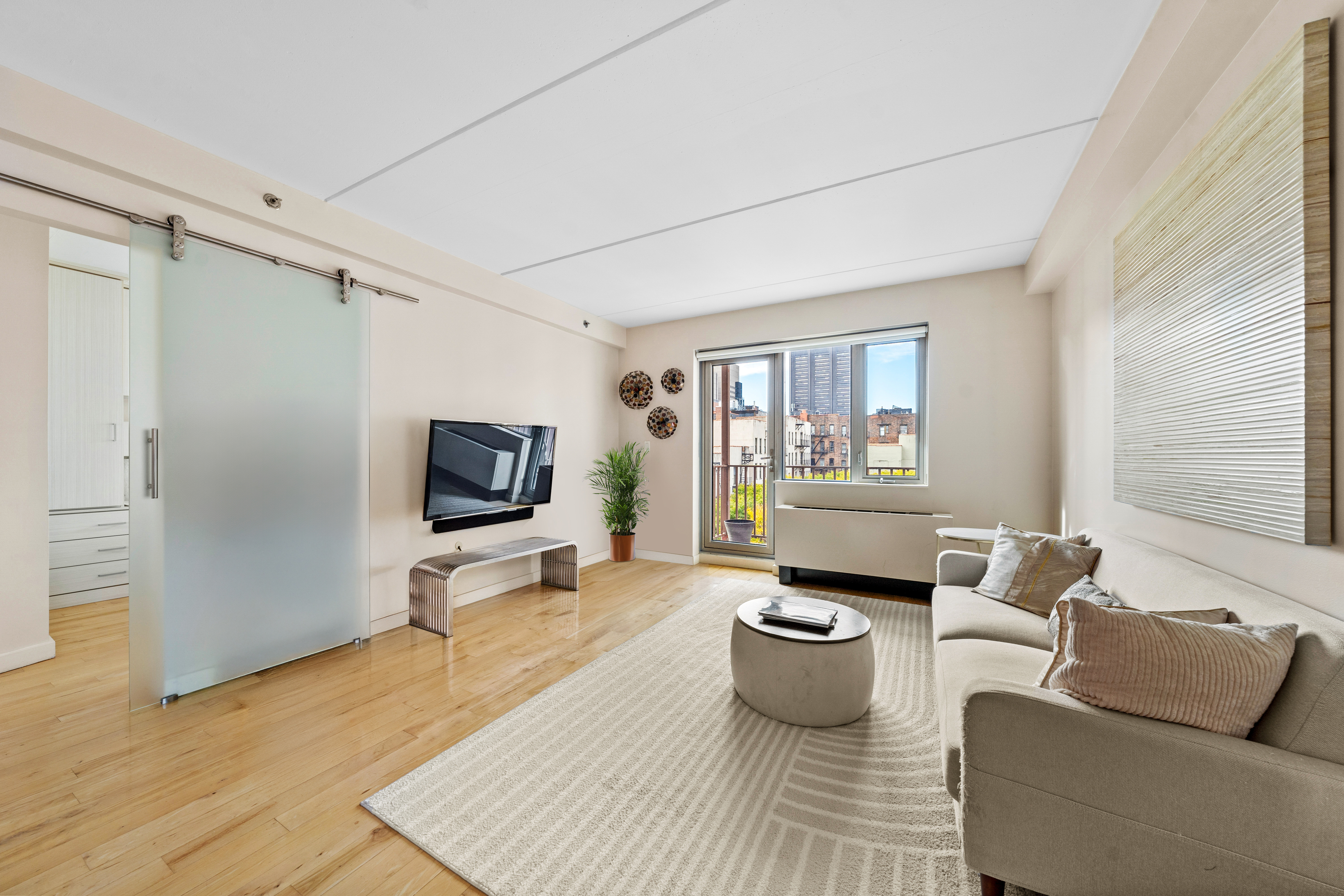 1810 3rd Avenue, Unit A9B Manhattan, NY 10029 - Photo 2 of 16 a living room with furniture and a flat screen tv