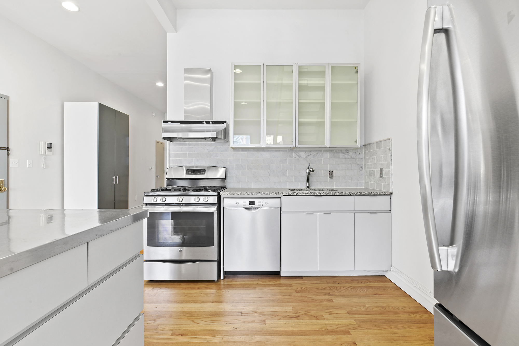 85 Division Street, Unit 4 Manhattan, NY 10002 - Photo 5 of 22 a kitchen with stainless steel appliances granite countertop a sink and a refrigerator