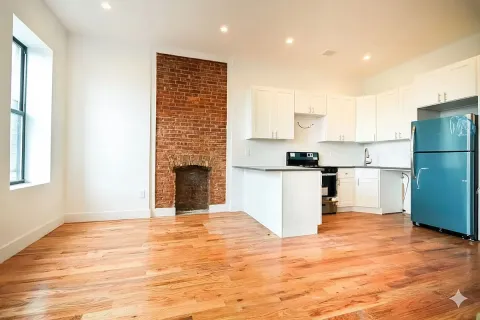 a view of kitchen with kitchen island a sink wooden floor and a refrigerator