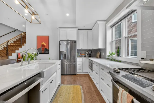 a kitchen with stainless steel appliances kitchen island hardwood floor sink stove and wooden cabinets