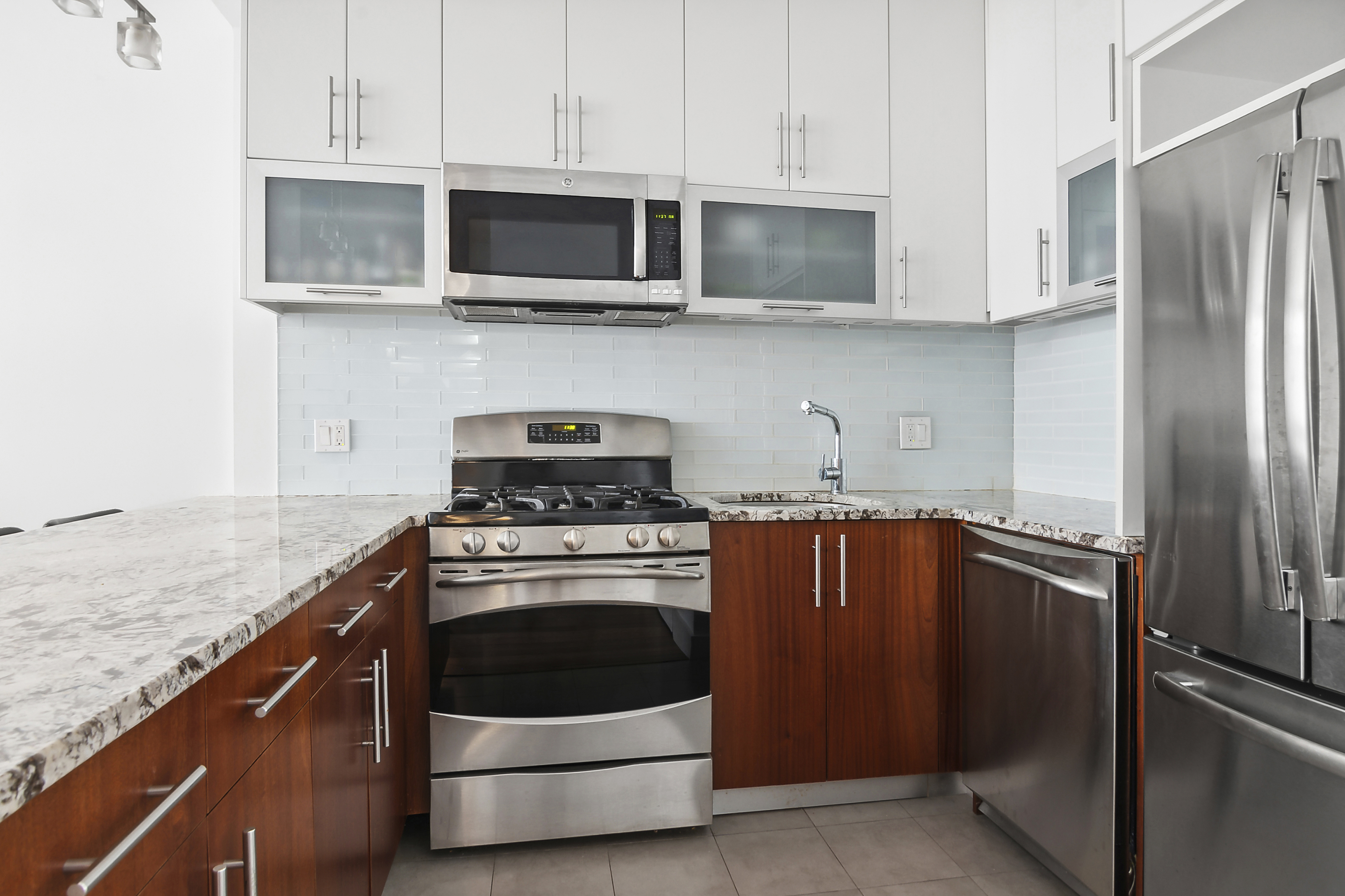 41-18 27th Street, Unit 4A Queens, NY 11101 - Photo 3 of 5 a kitchen with stainless steel appliances granite countertop a stove microwave and refrigerator