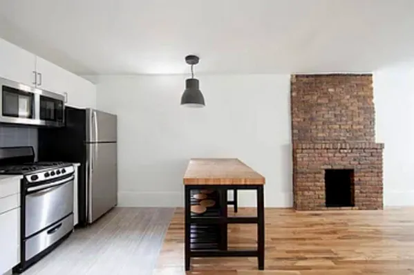 a kitchen with stainless steel appliances kitchen island wooden cabinets and a fireplace