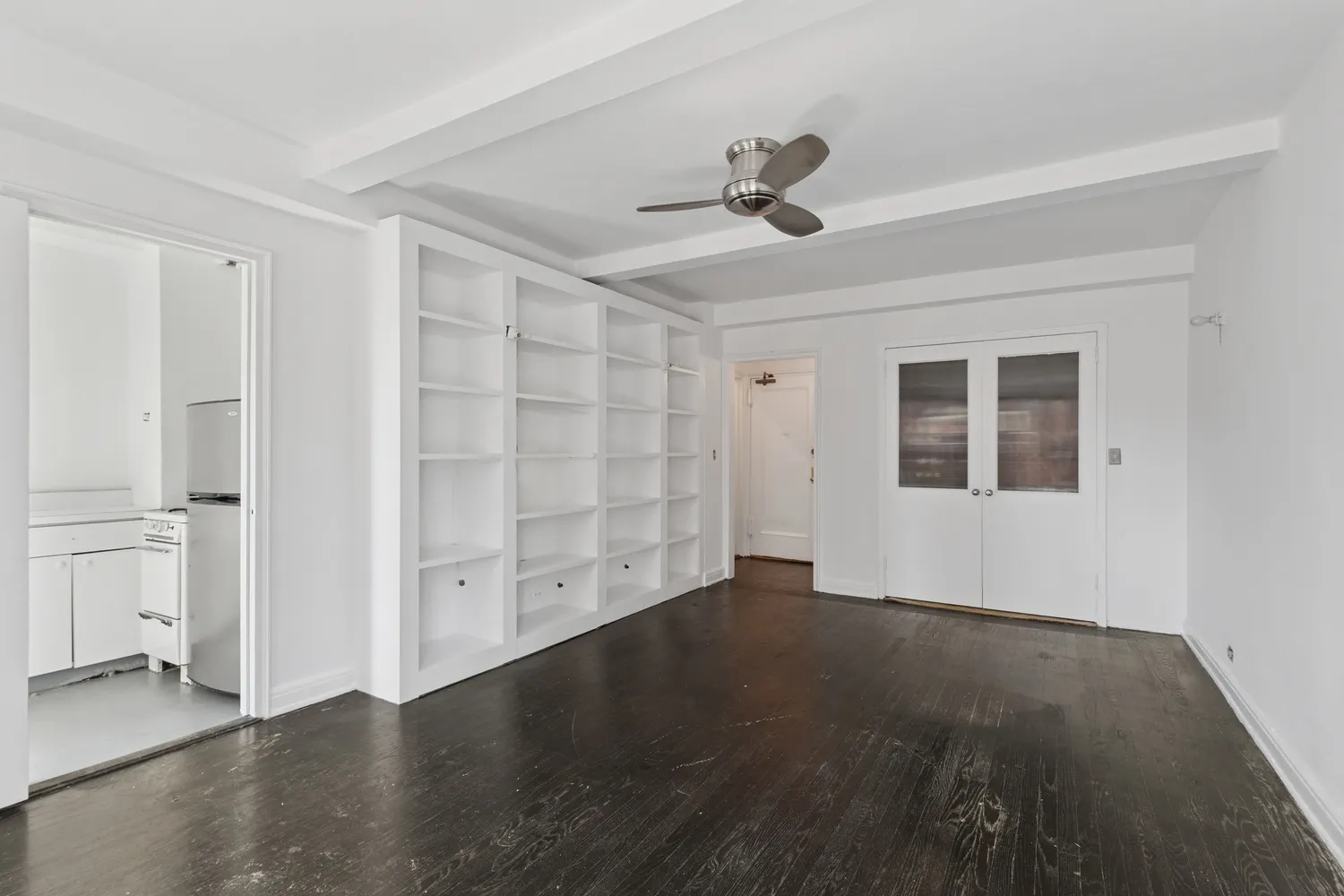 a view of an empty room with wooden floor and a window