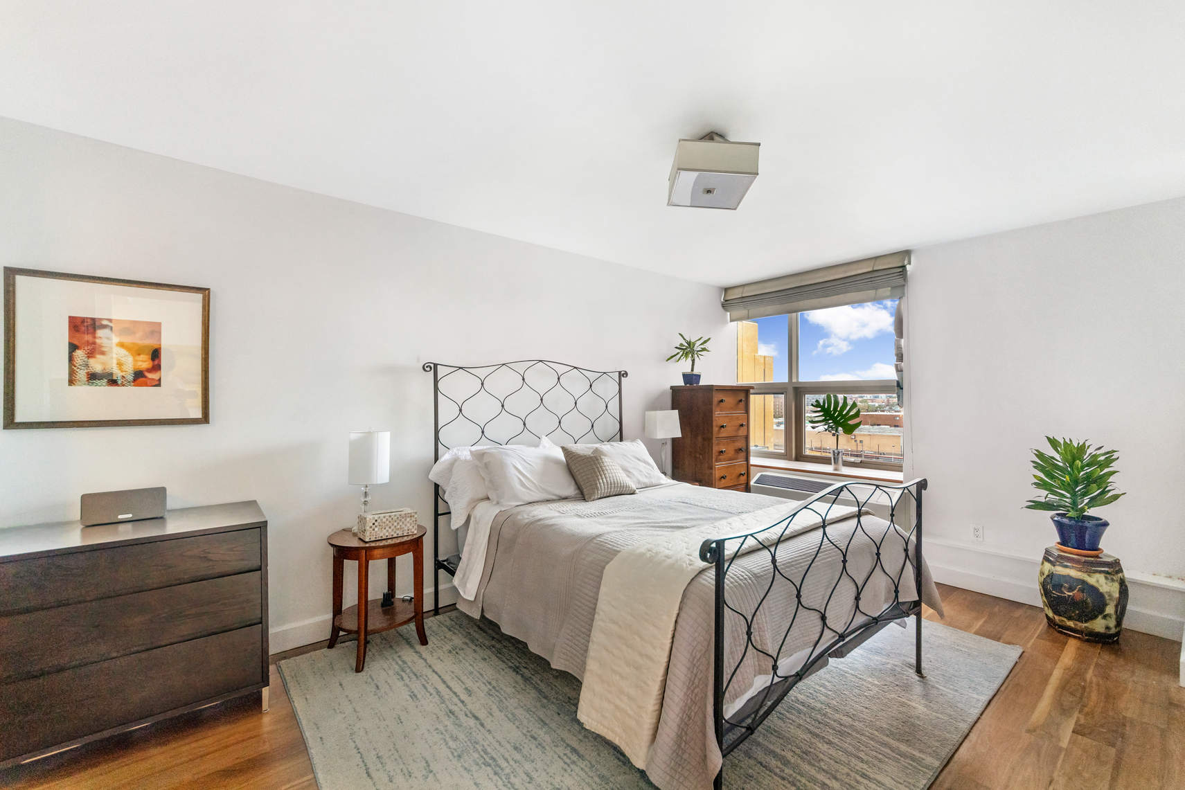 2-17 51st Avenue, Unit 606 Queens, NY 11101 - Photo 5 of 18 a bedroom with a bed and a potted plant on dresser