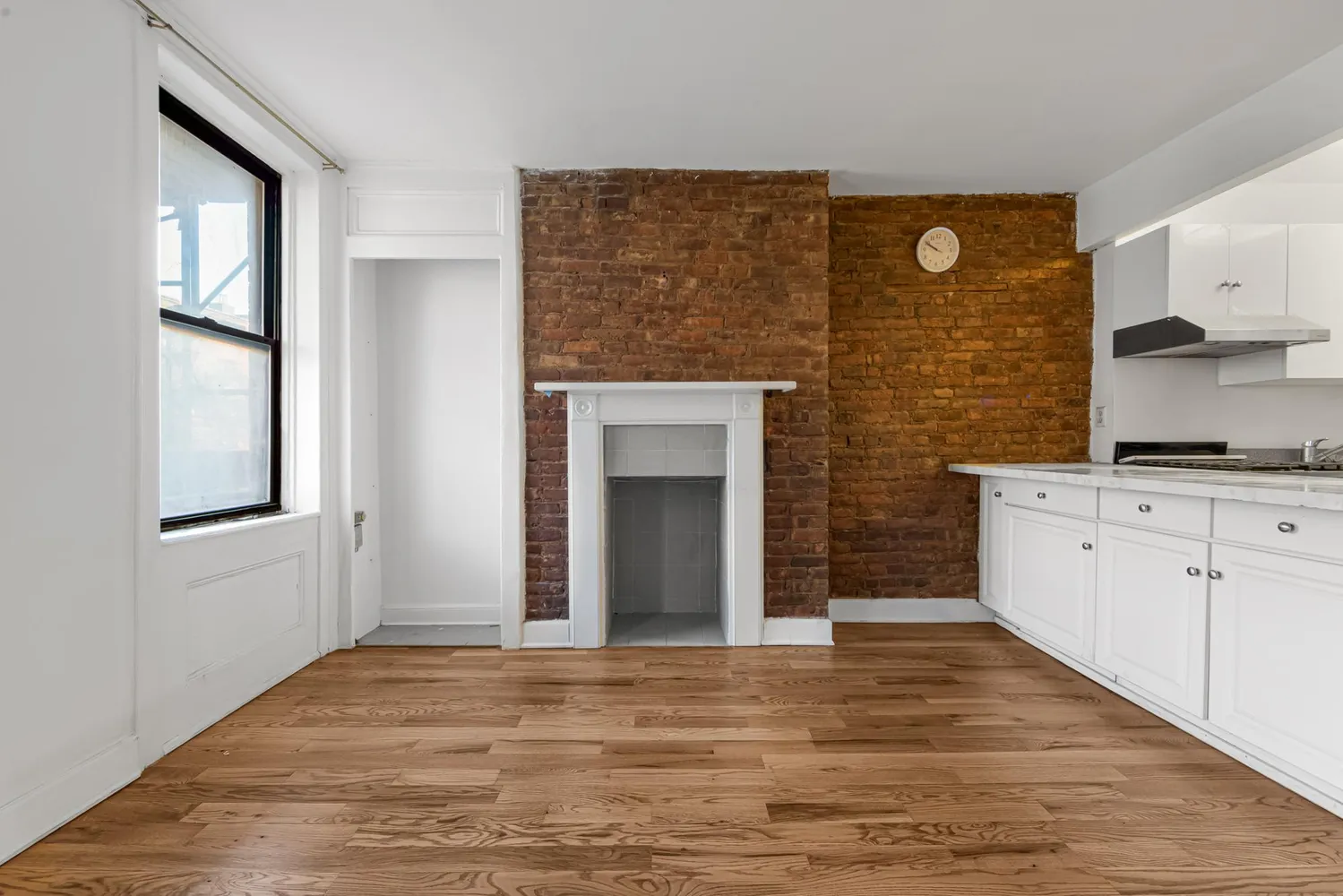 a view of a kitchen with wooden floor and a fireplace