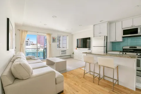 a living room with furniture a flat screen tv and a refrigerator