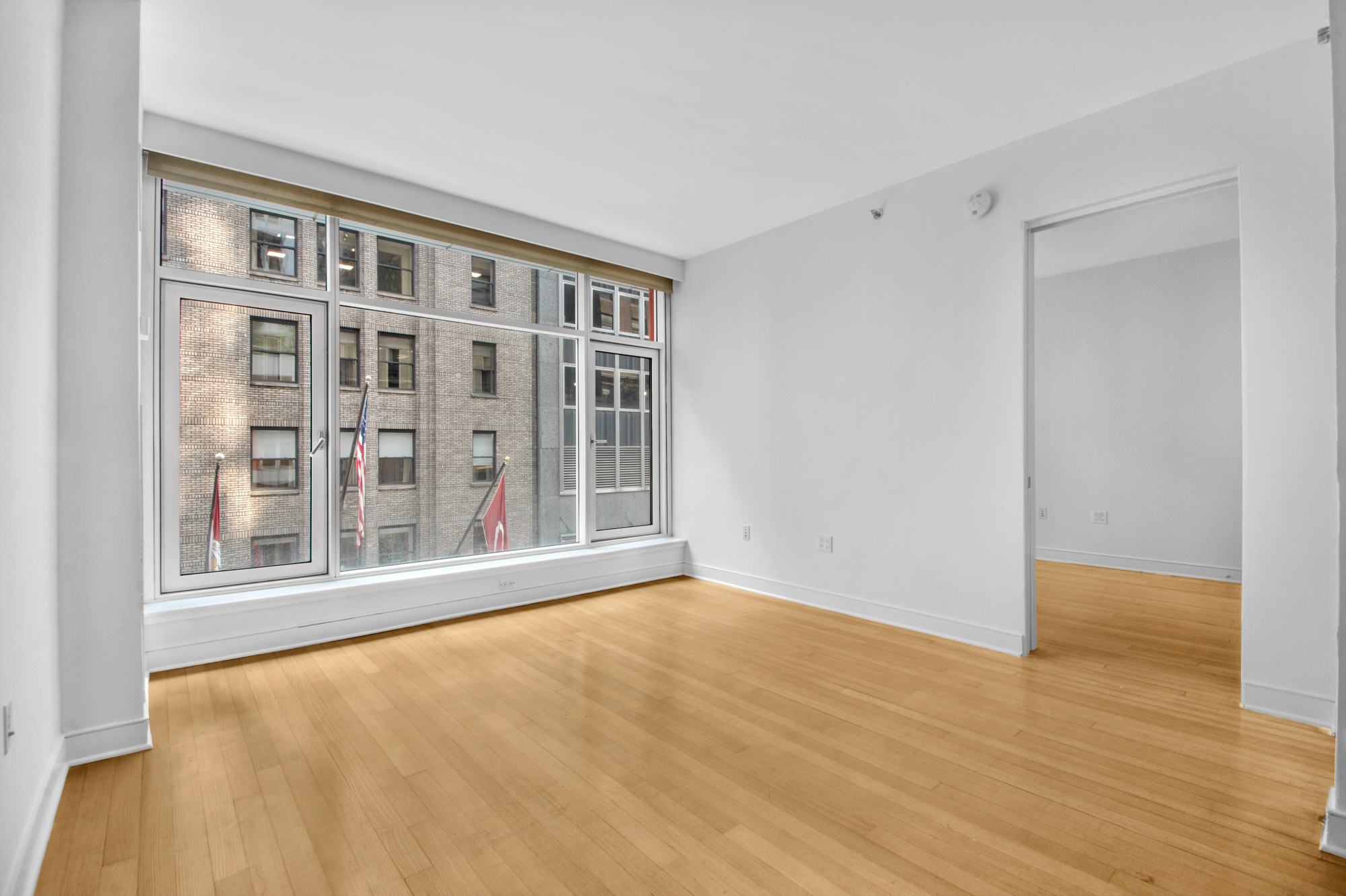 5 East 44th Street, Unit 5A Manhattan, NY 10017 - Photo 3 of 15 a view of an empty room with wooden floor and a window