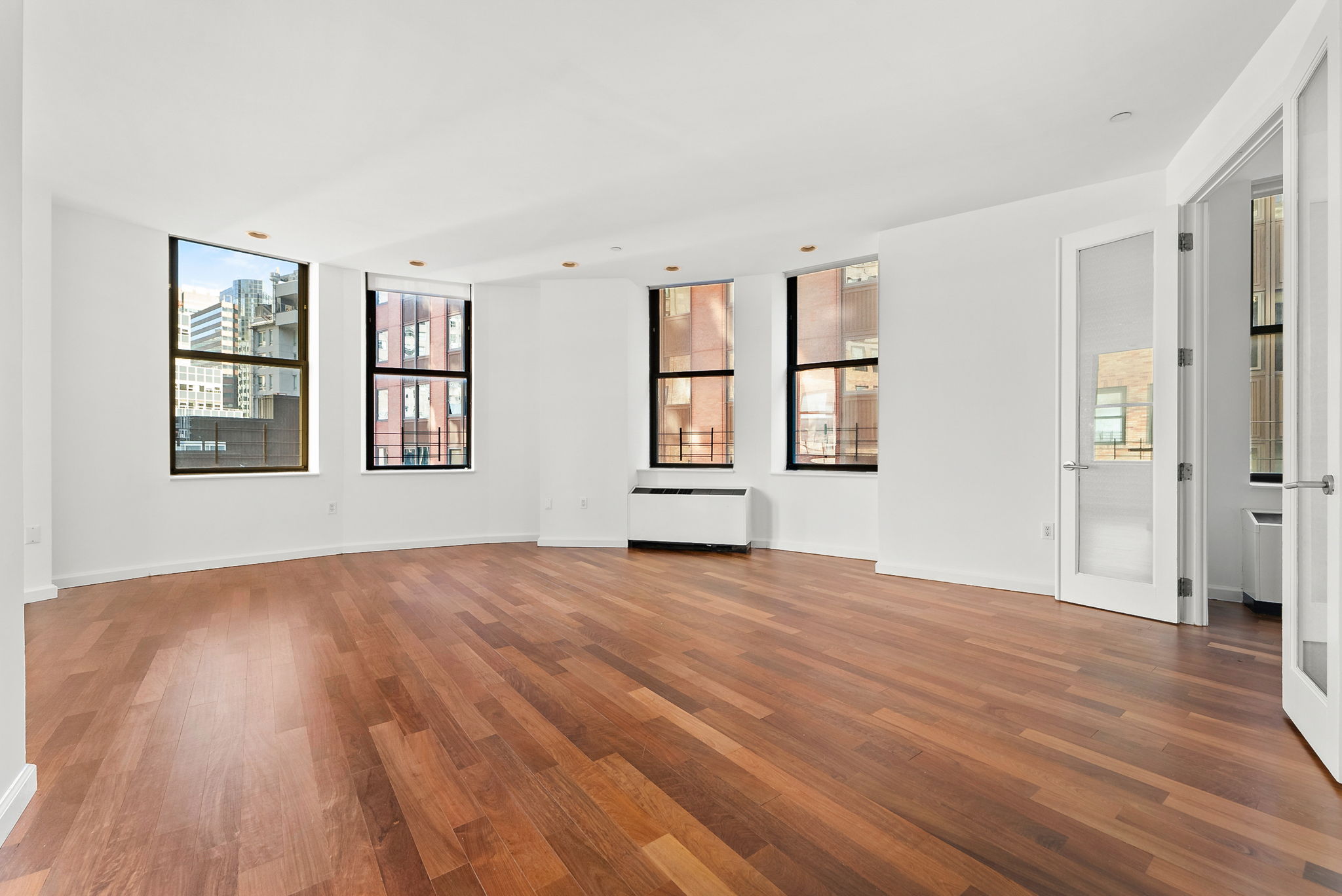 1 Wall Street Court, Unit 1405 Manhattan, NY 10005 - Photo 5 of 19 a view of empty room with wooden floor and fan