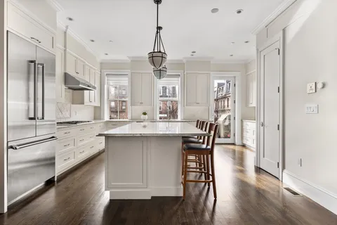 a kitchen with stainless steel appliances granite countertop a dining table chairs a sink and dishwasher a refrigerator with wooden floor