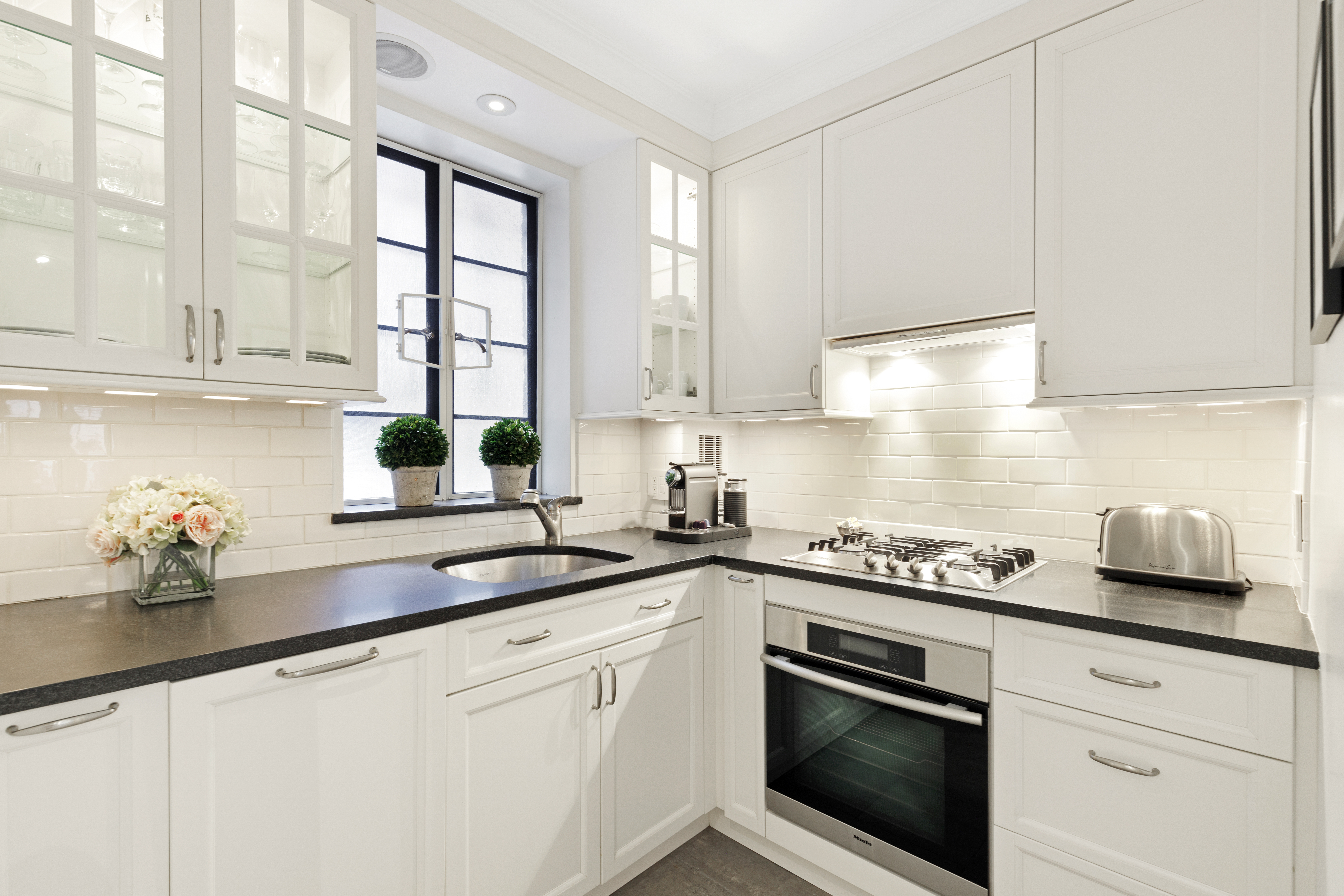 110 East 87th Street, Unit 2C Manhattan, NY 10128 - Photo 6 of 12 a kitchen with stainless steel appliances white cabinets and a window