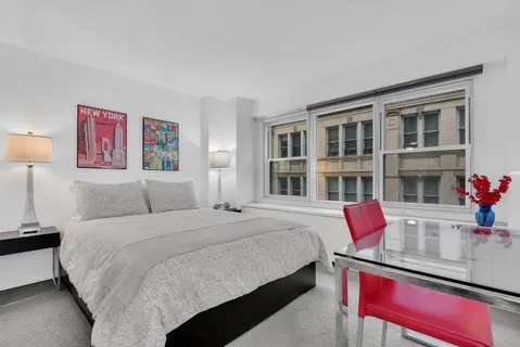a bedroom with a bed and a potted plant on dresser