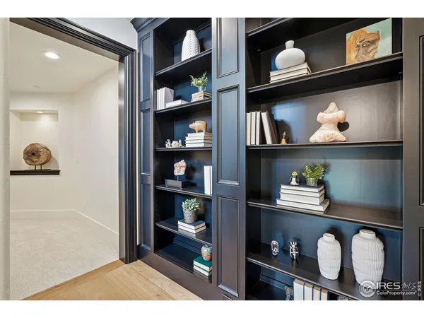 a picture of a book shelf of a room with lots of books and painting on the wall