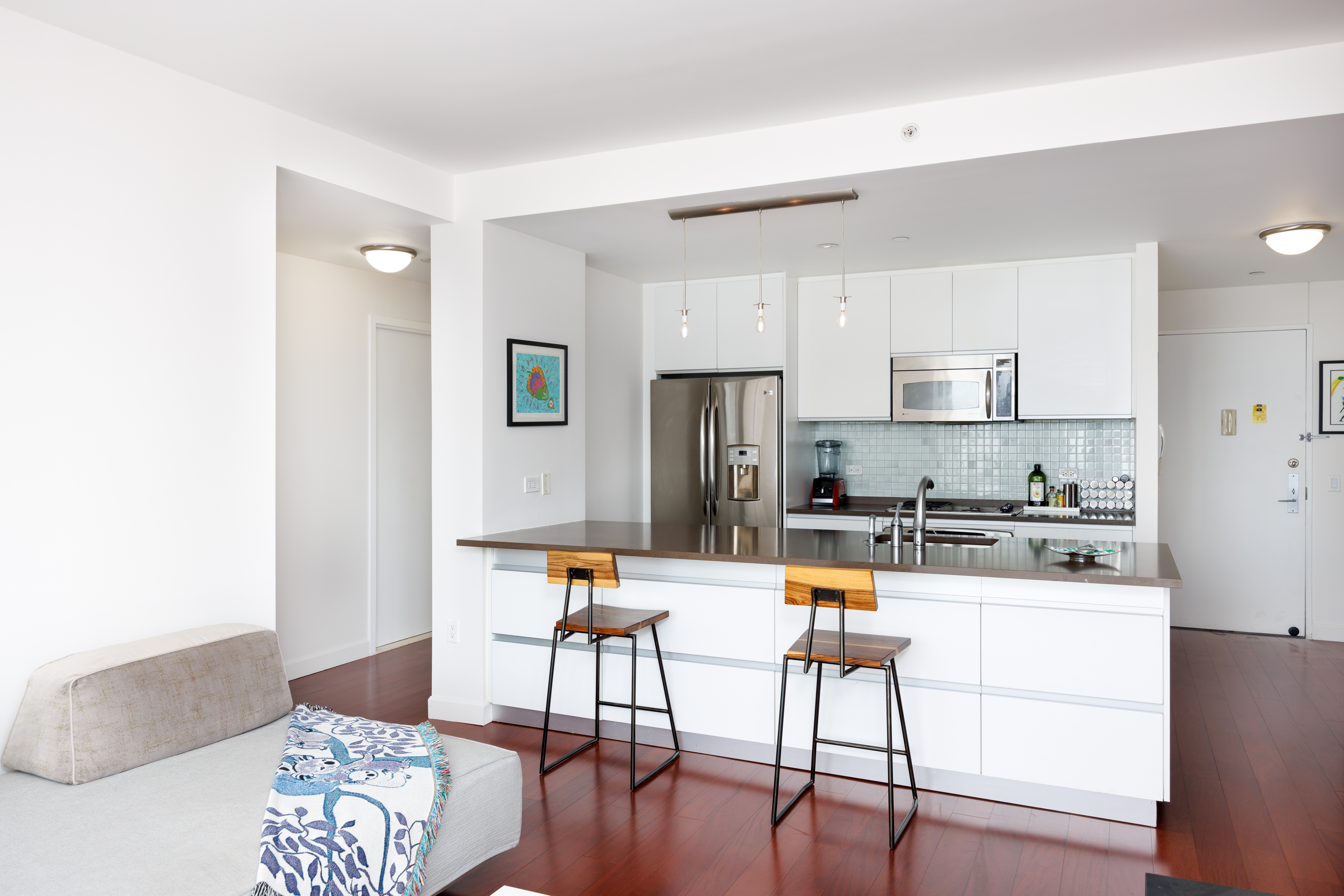 306 Gold Street, Unit 33E Brooklyn, NY 11201 - Photo 4 of 8 a kitchen with stainless steel appliances kitchen island granite countertop a refrigerator a stove a microwave oven with white cabinets and wooden floor