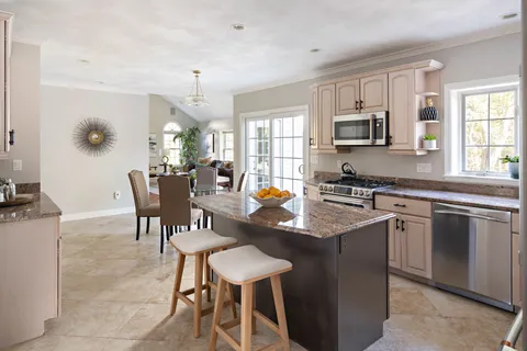 a kitchen with kitchen island granite countertop a sink counter top space appliances and a window