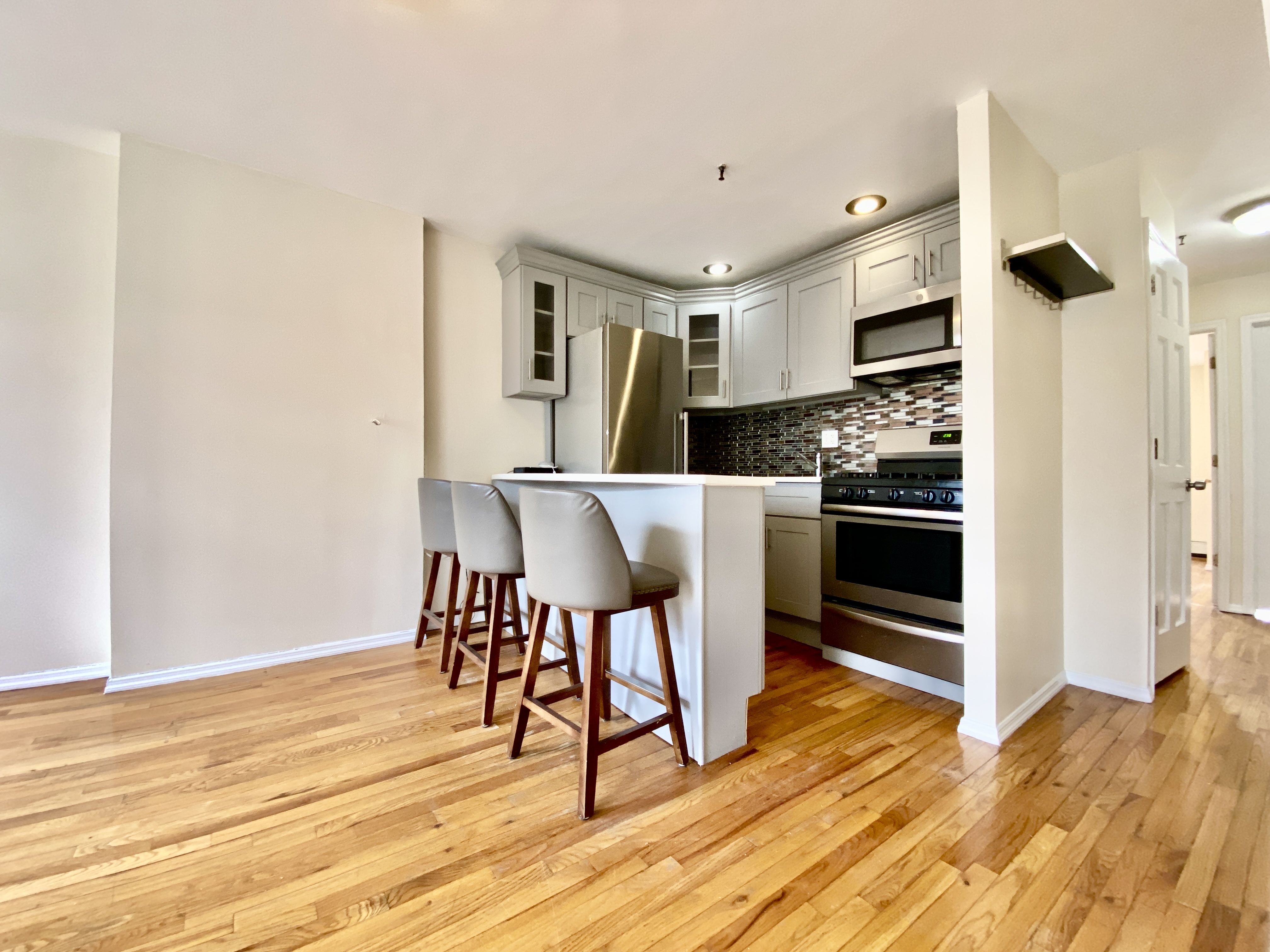 a kitchen with stainless steel appliances a dining table chairs and refrigerator