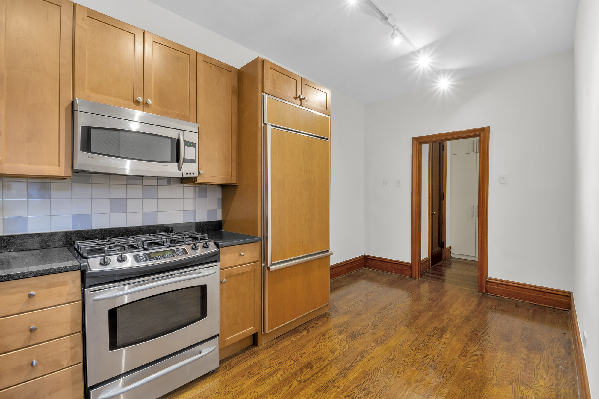 790 Riverside Drive, Unit 5F Manhattan, NY 10032 - Photo 10 of 12 a kitchen with granite countertop wooden cabinets and stainless steel appliances