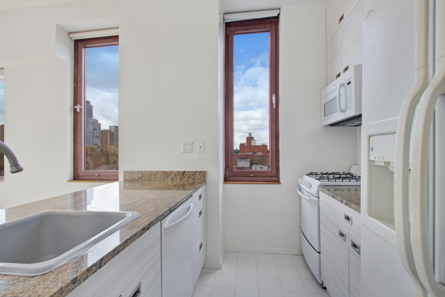 393 West 49th Street, Unit 6G Manhattan, NY 10019 - Photo 5 of 11 a kitchen with granite countertop a sink stove and refrigerator