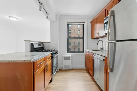 a kitchen with stainless steel appliances granite countertop a refrigerator a stove and a sink with wooden floor