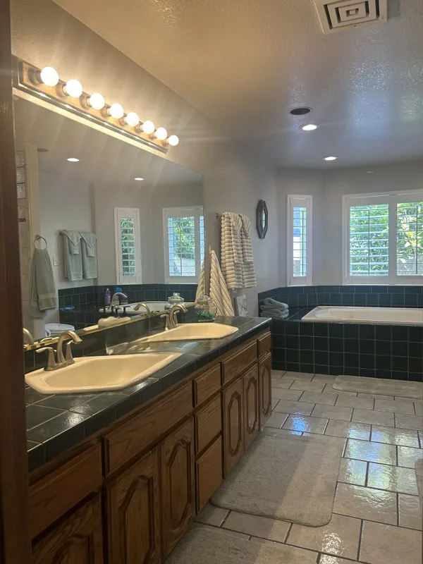 a spacious bathroom with a granite countertop sink a mirror and a bathtub