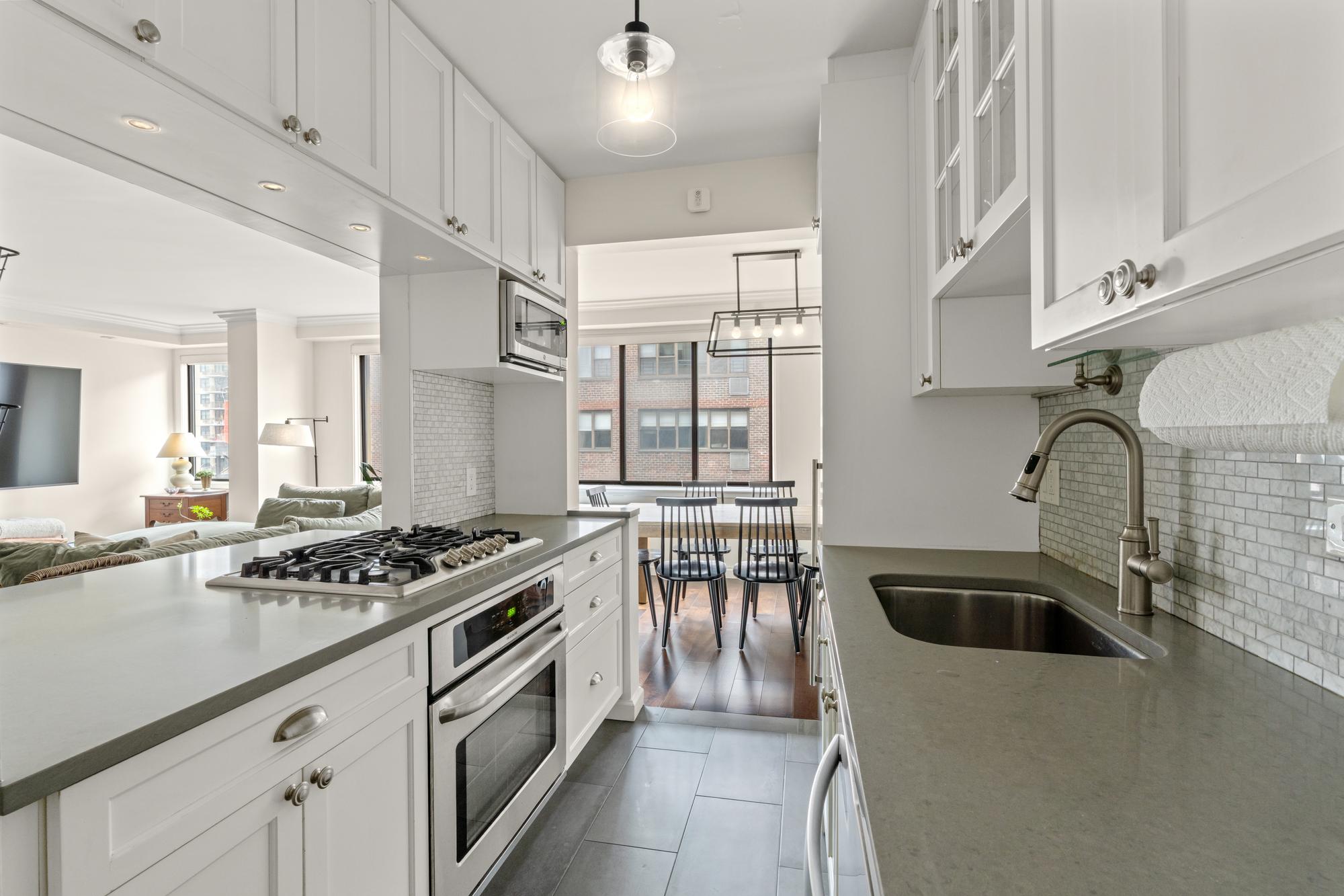 345 East 73rd Street, Unit 11KL Manhattan, NY 10021 - Photo 5 of 12 a kitchen with granite countertop a stove and a sink