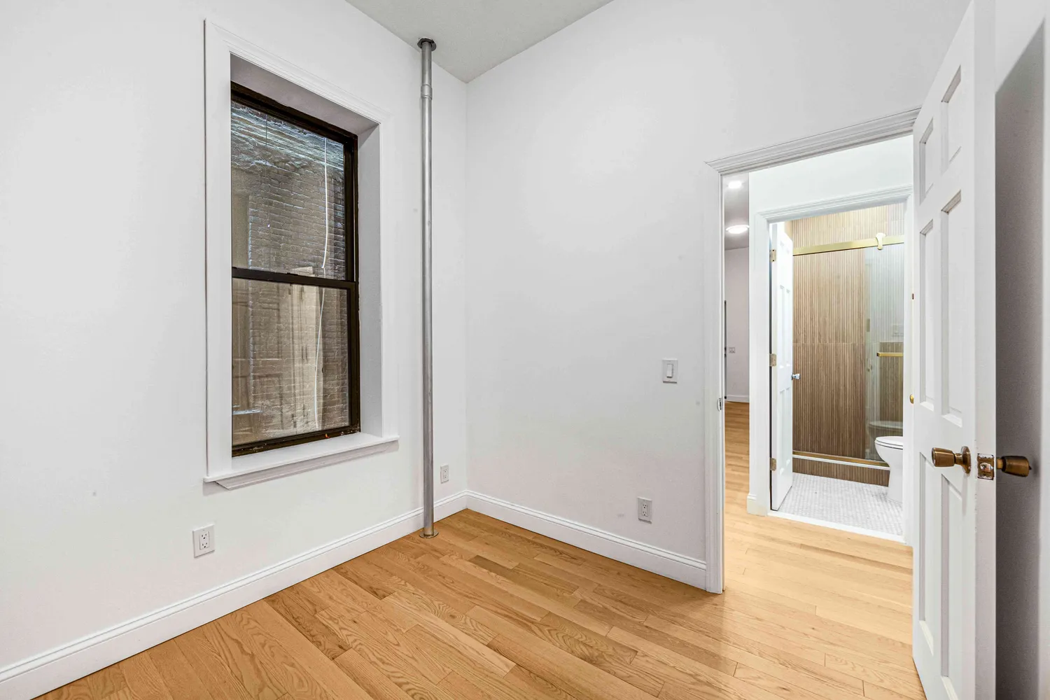 an empty room with wooden floor and a window