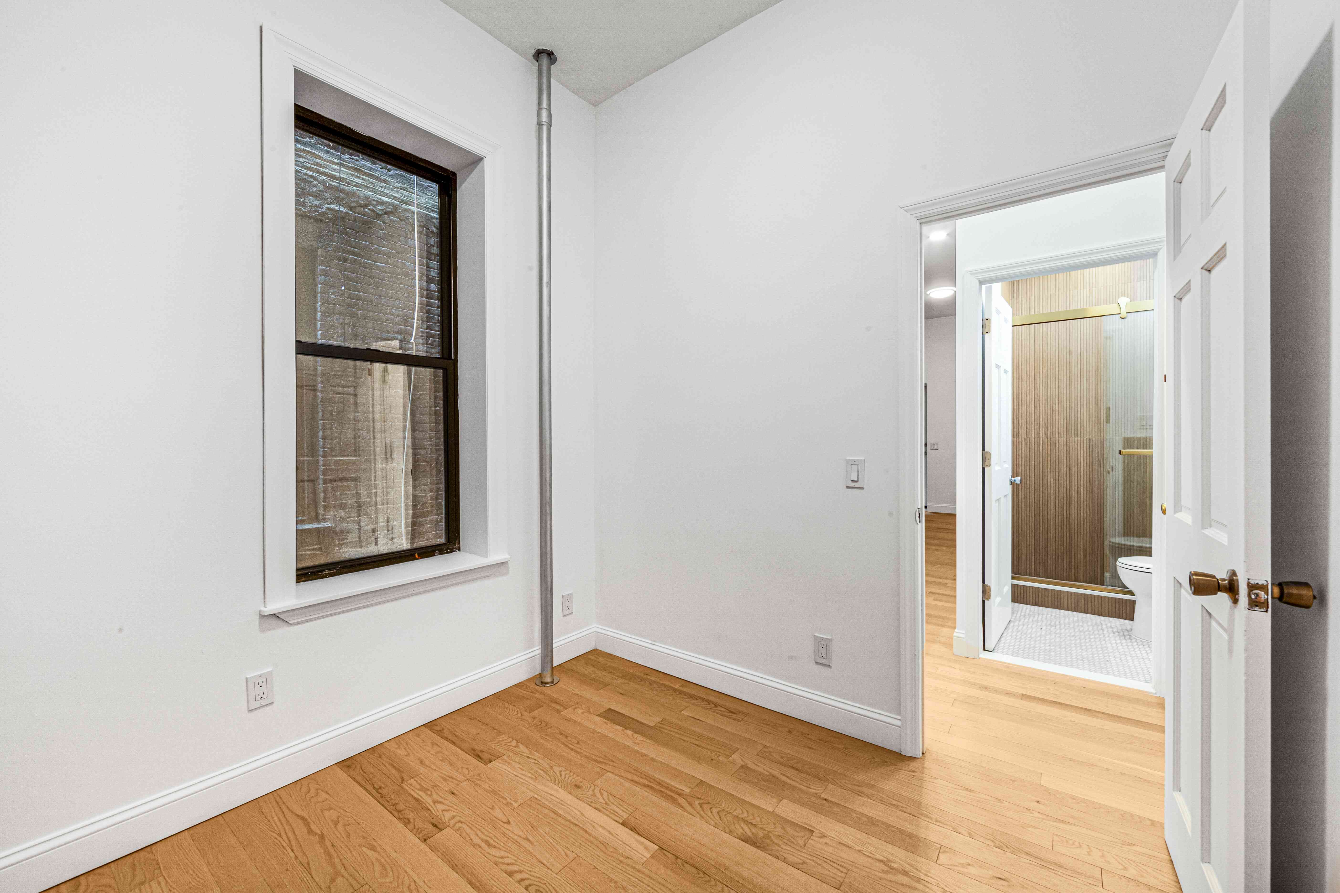 304 East 11th Street, Unit 1C Manhattan, NY 10003 - Photo 15 of 16 an empty room with wooden floor and a window