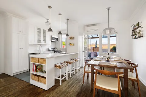 a room with stainless steel appliances kitchen island granite countertop a table chairs and a wooden floor