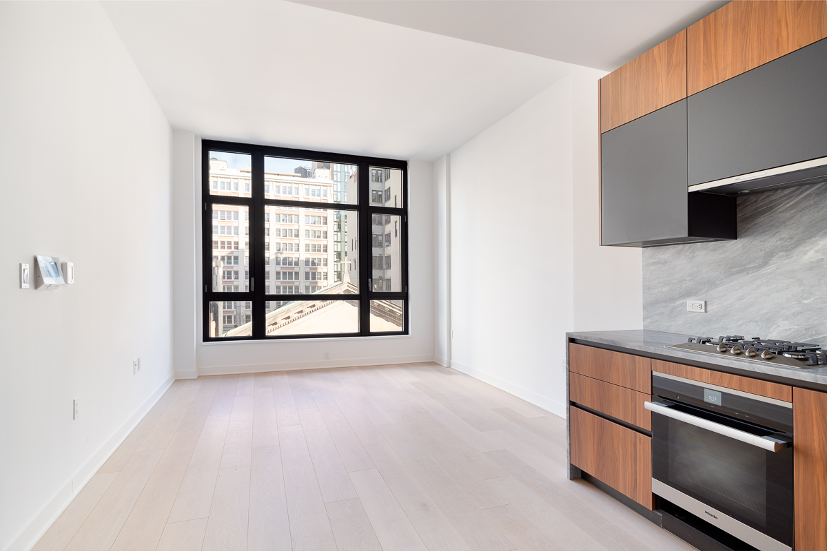 128 West 23rd Street, Unit 7C Manhattan, NY 10011 - Photo 1 of 5 a view of an empty room with a window and kitchen view