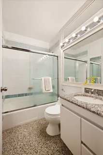 a bathroom with a granite countertop sink mirror vanity and toilet