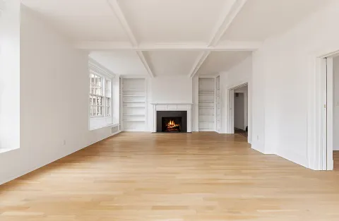 a view of an empty room with a window and fireplace