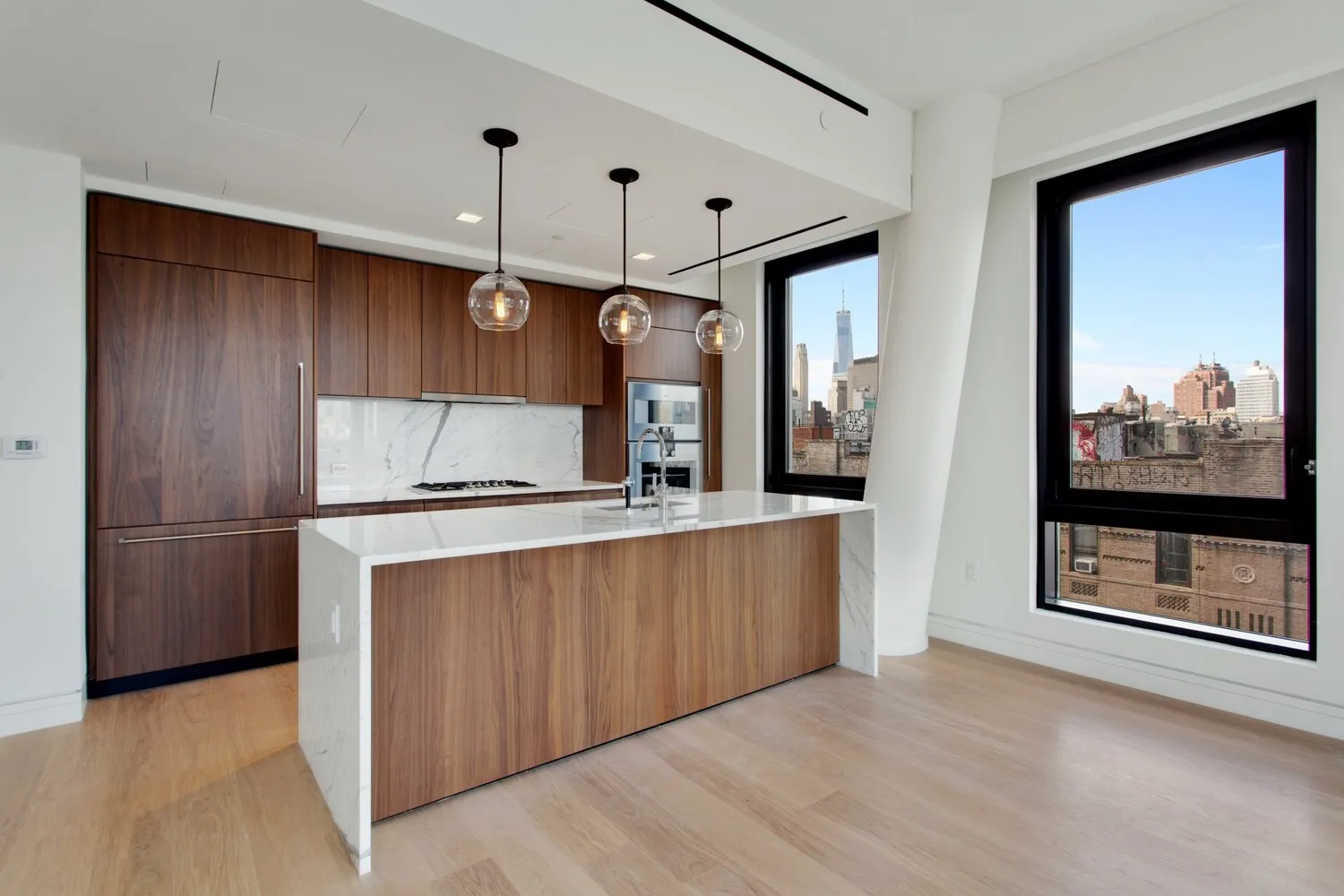 a kitchen with stainless steel appliances granite countertop a refrigerator a oven and a sink with wooden floors