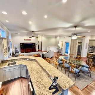 a living room with stainless steel appliances furniture a rug and a kitchen view