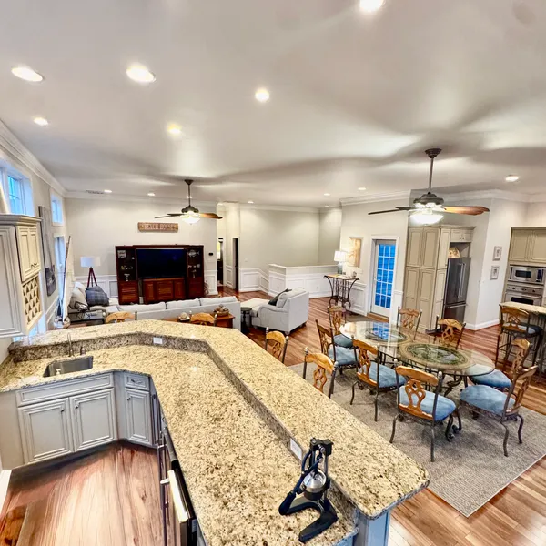 a living room with stainless steel appliances furniture a rug and a kitchen view