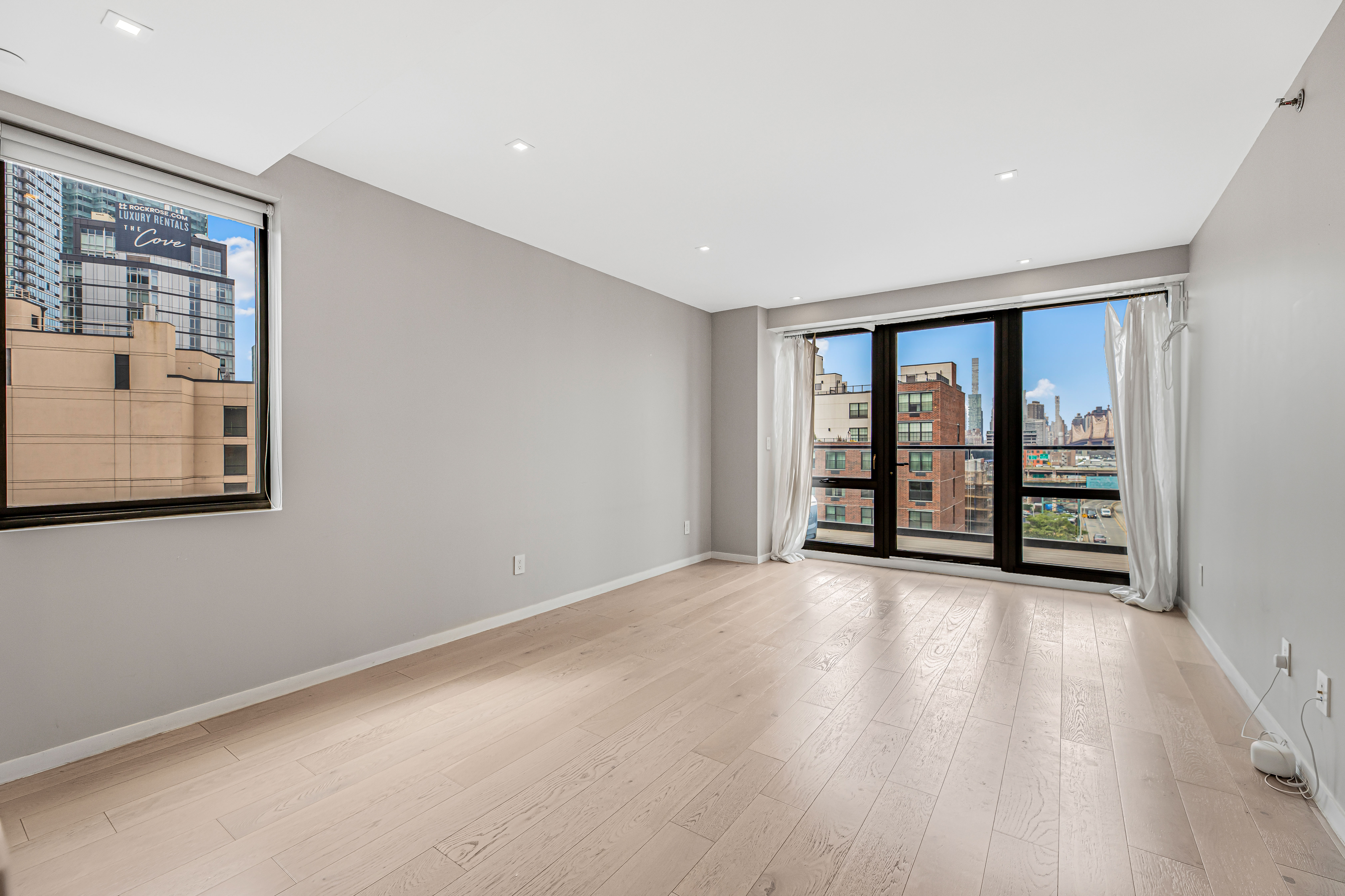 42-50 27th Street, Unit 9C Queens, NY 11101 - Photo 16 of 32 wooden floor in an empty room with a window