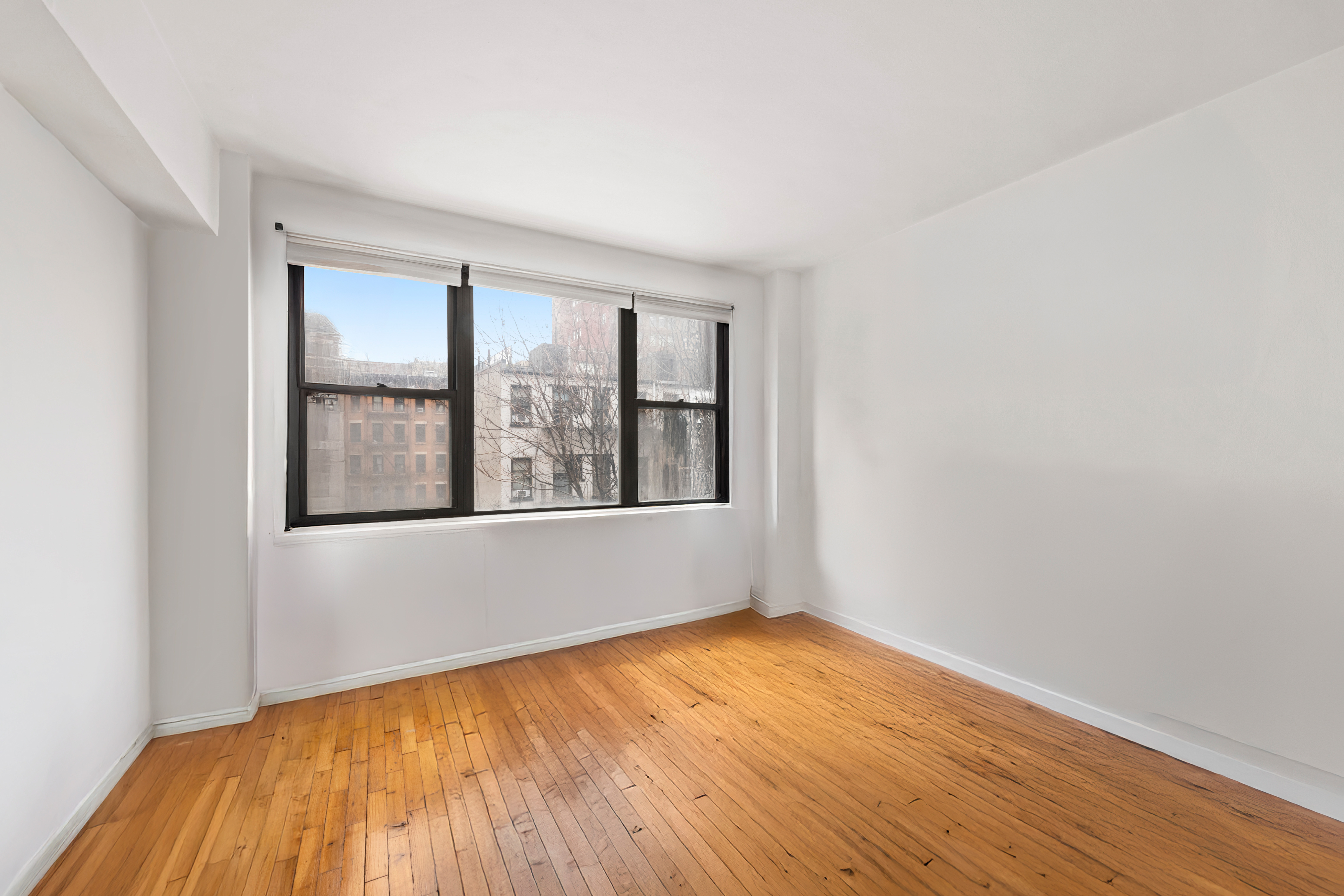 408 West 57th Street, Unit 3A Manhattan, NY 10019 - Photo 8 of 11 an empty room with wooden floor and windows
