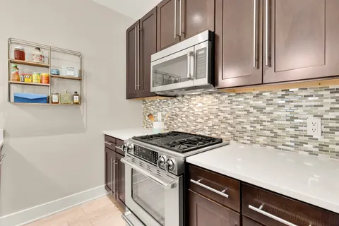 a kitchen with granite countertop cabinets stove top oven and microwave