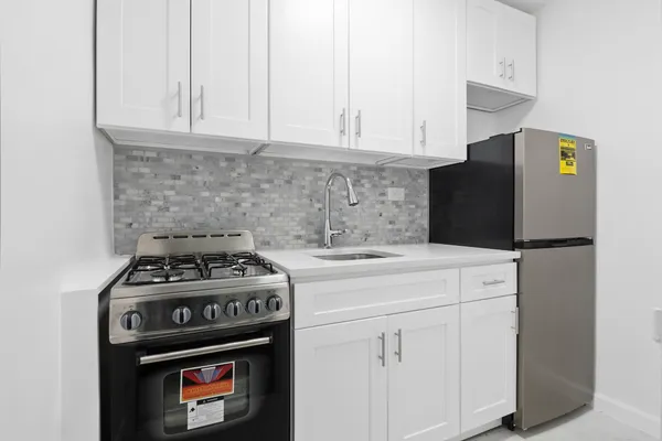 a kitchen with stainless steel appliances granite countertop a stove a refrigerator and a white cabinets