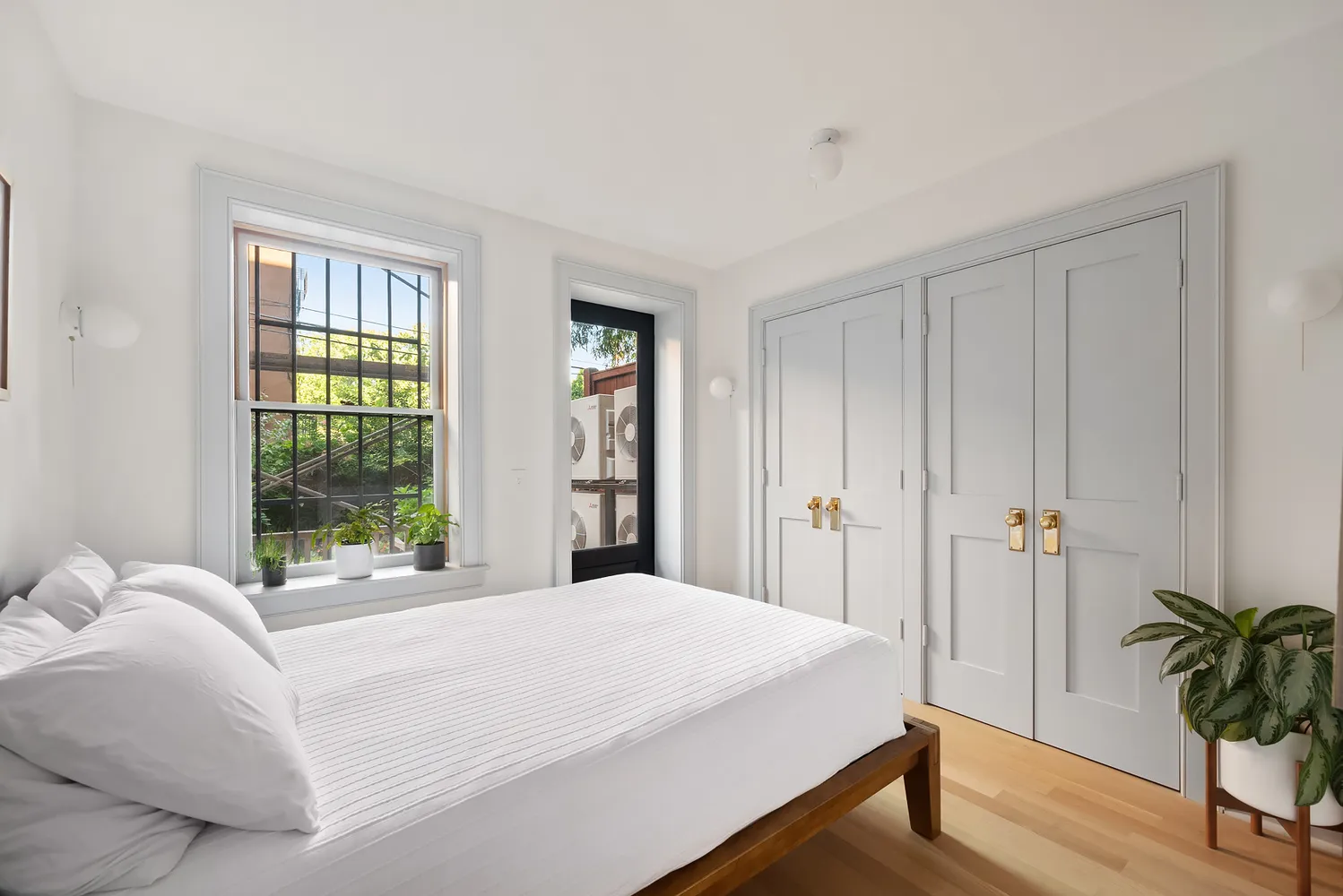 a bedroom with a bed and a potted plant next to a window