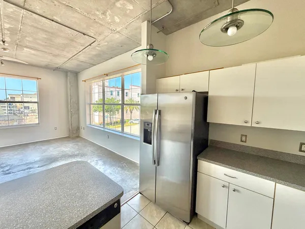 a kitchen with stainless steel appliances granite countertop a refrigerator a sink and white cabinets