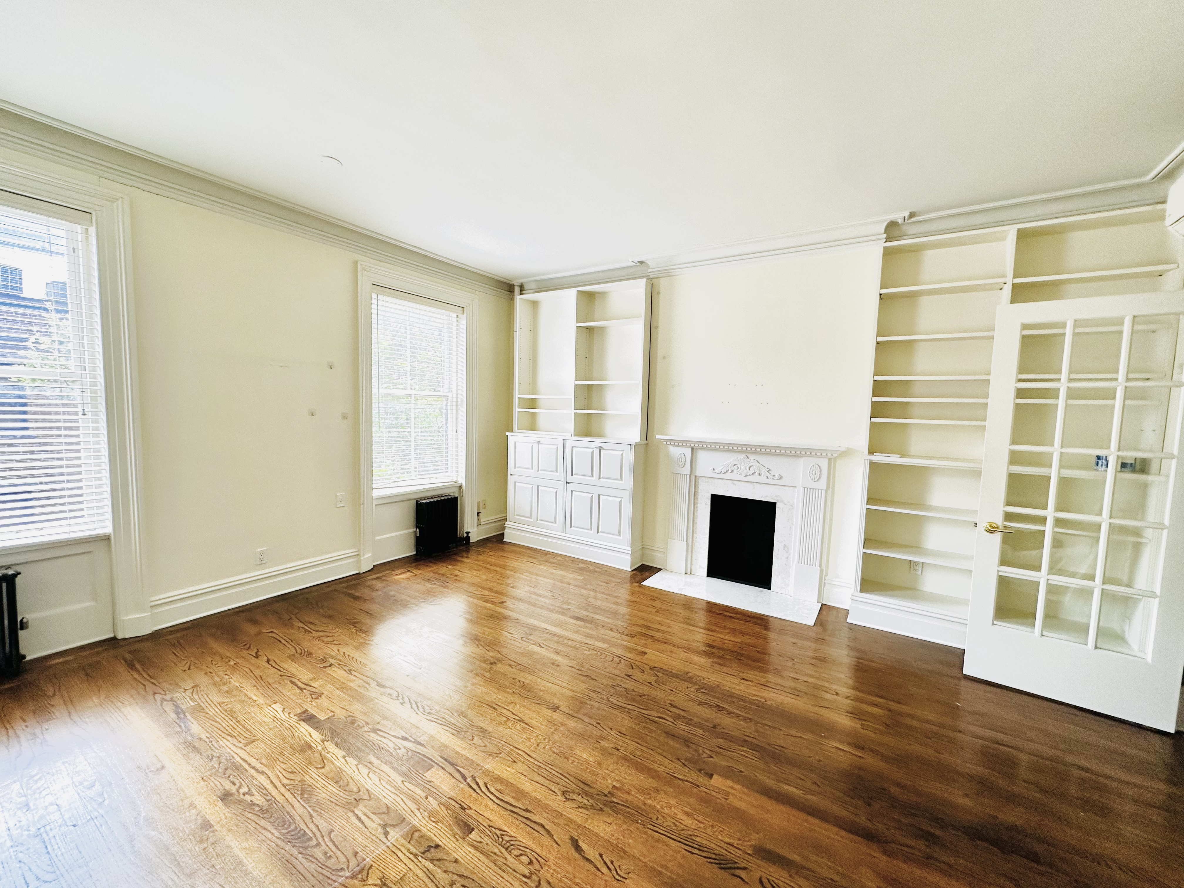 an empty room with wooden floor fireplace and windows