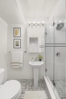 a bathroom with a sink a toilet a mirror and shower