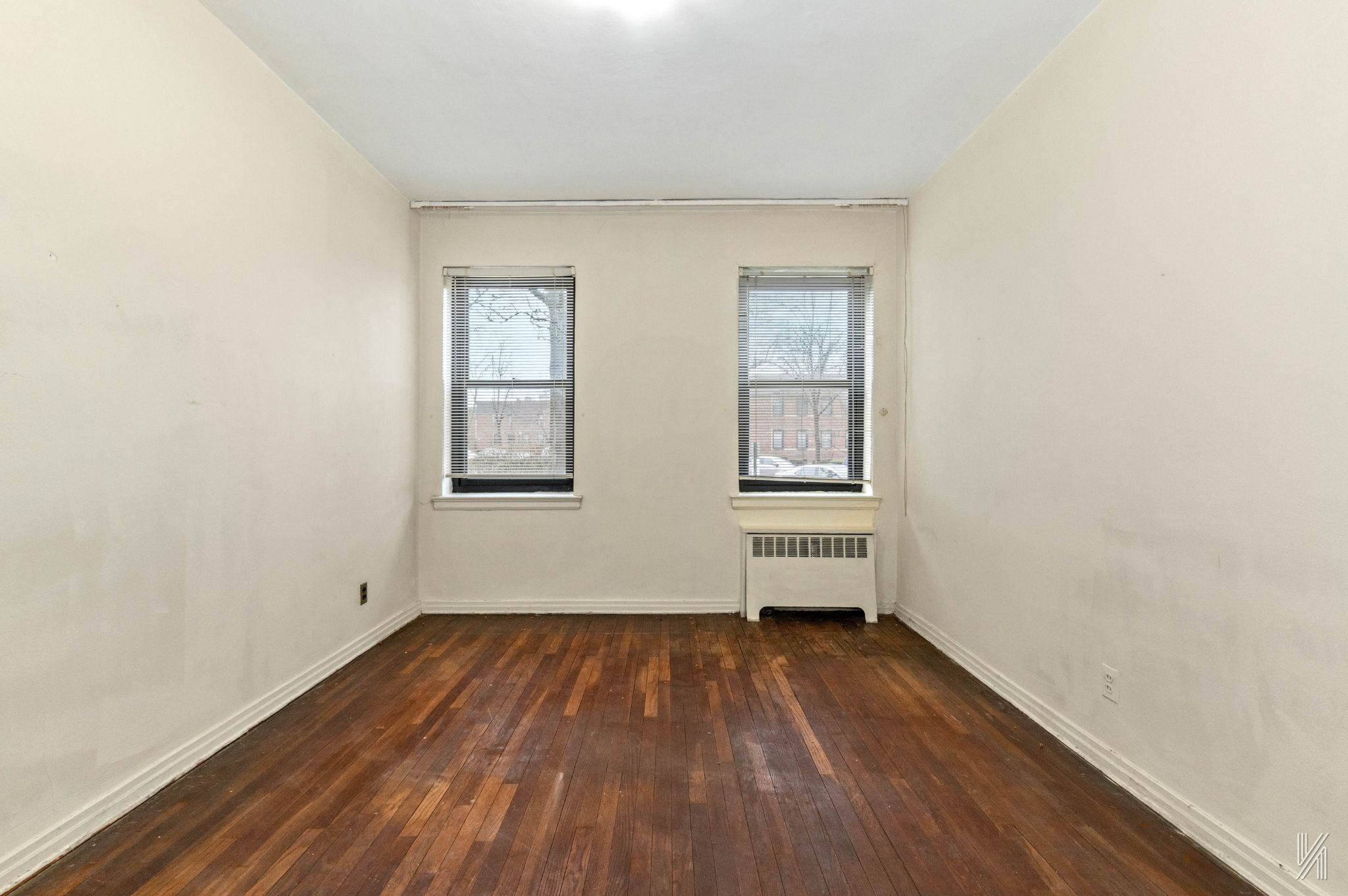 22-60 79th Street, Unit 1A Queens, NY 11370 - Photo 9 of 17 an empty room with wooden floor and windows
