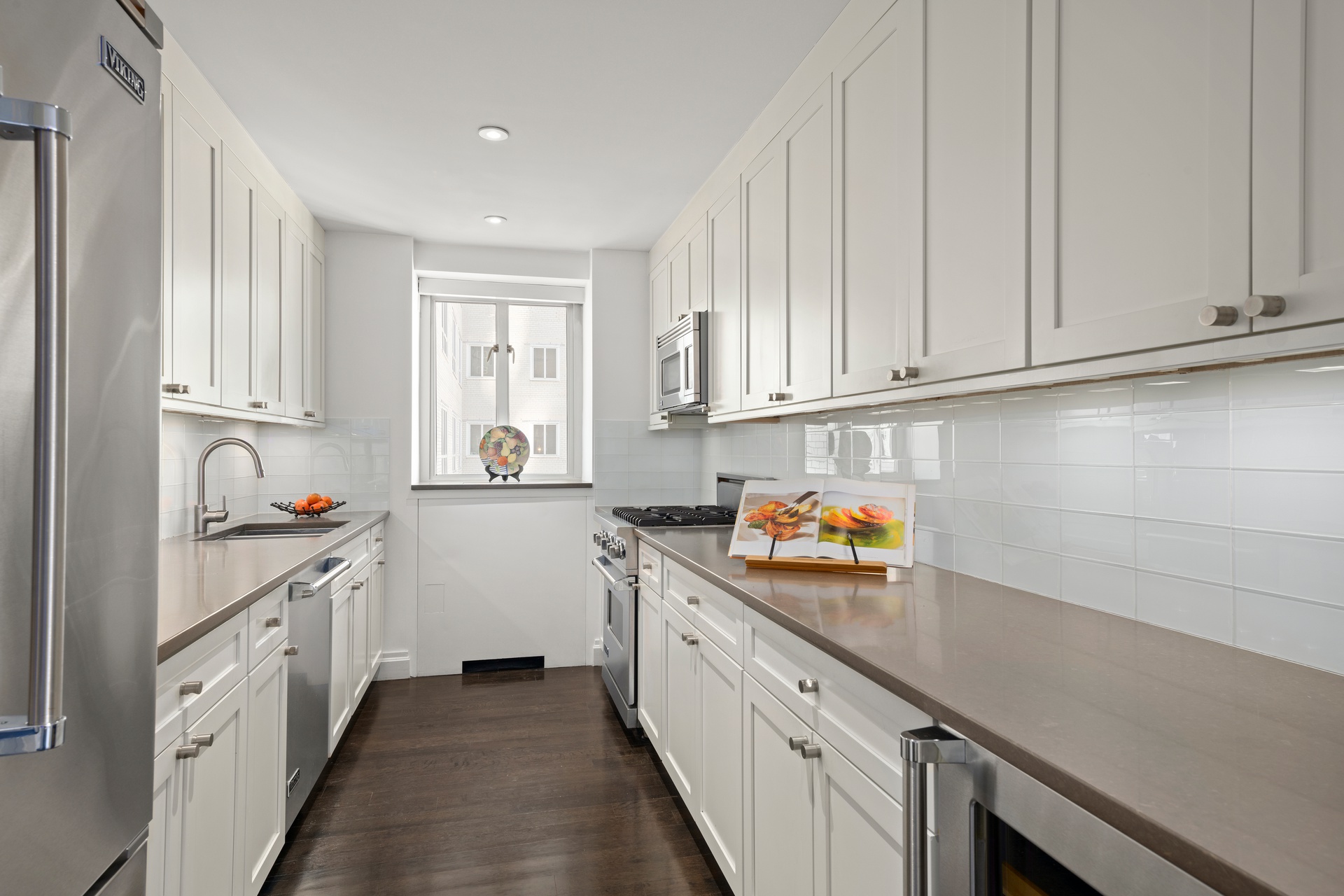 200 East 66th Street, Unit D1205 Manhattan, NY 10065 - Photo 5 of 33 a kitchen with stainless steel appliances white cabinets and a window